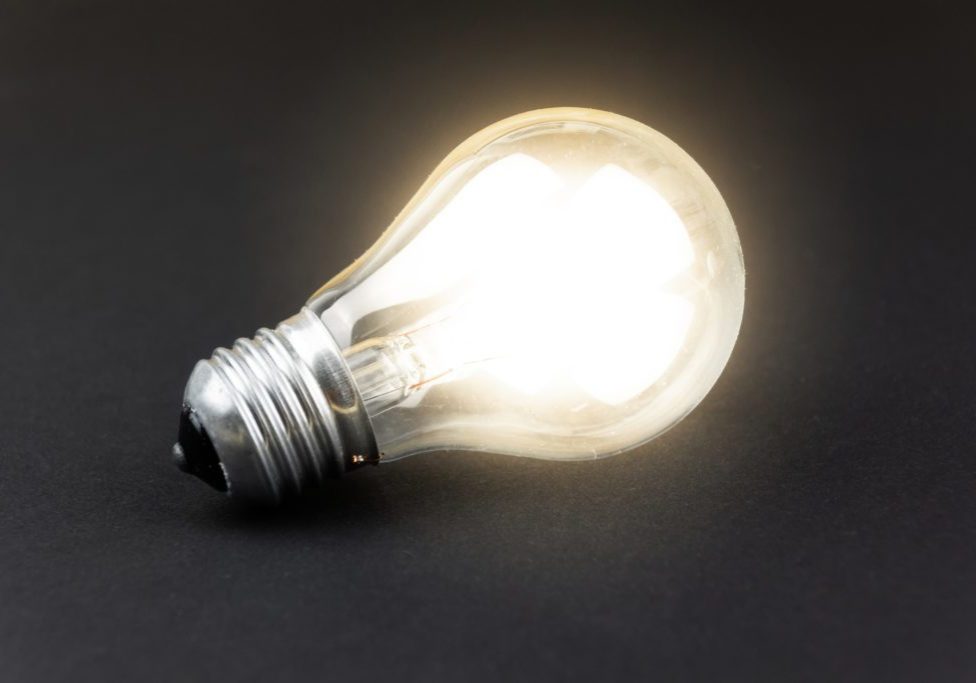 a lighted light bulb lies on a black cardboard