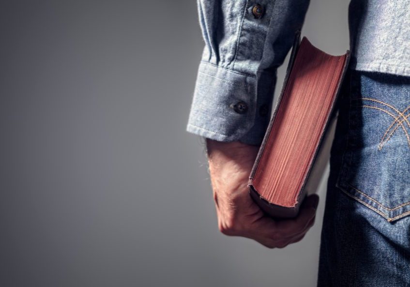 Man holding holy bible over gray background for copy concept for religion, praying, education and bible study