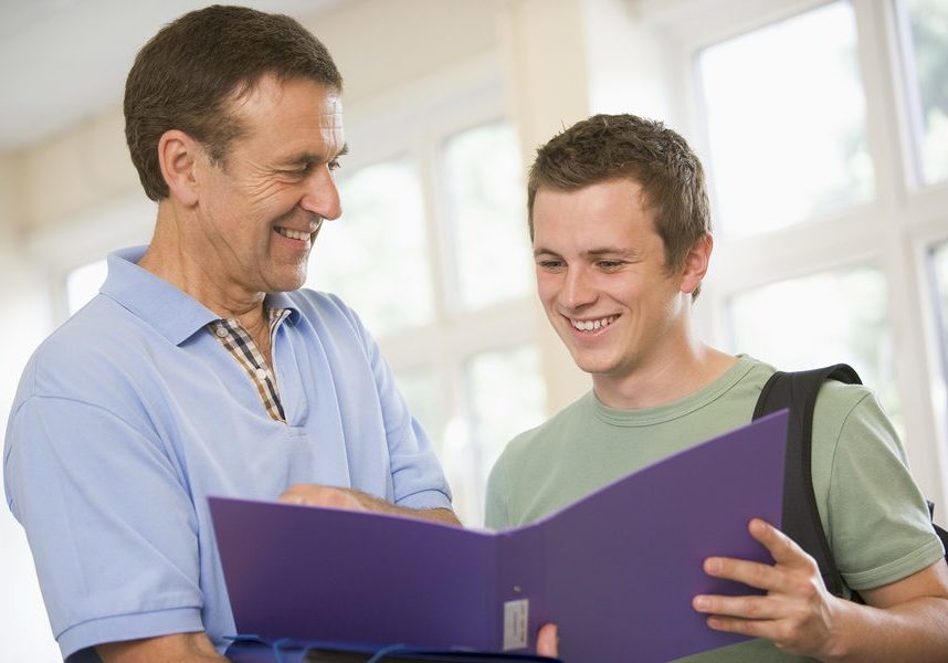 Teacher in corridor talking to student with notebooks