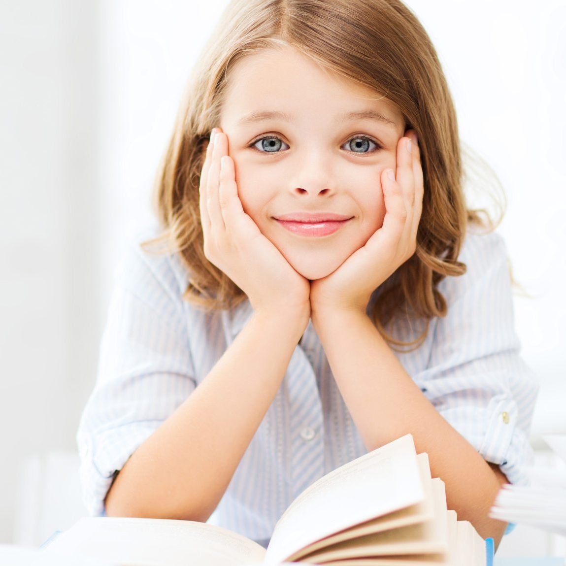 education and school concept - little student girl studying and reading books at school